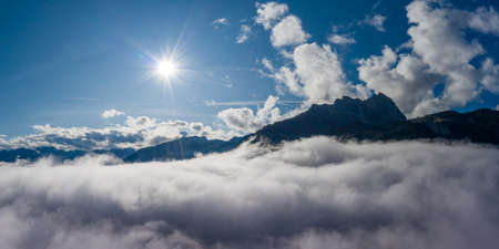 misty view to mount hahnenkamm at hoefen reutte with cloud bank and sun beamsの写真素材