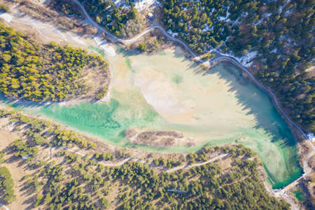aerial view to lake Huettenmuehle from above aith forest and road in Tirol