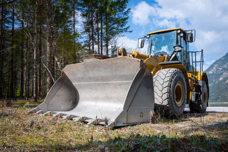 near perspective view to huge wheel loader with big shovel at forest
