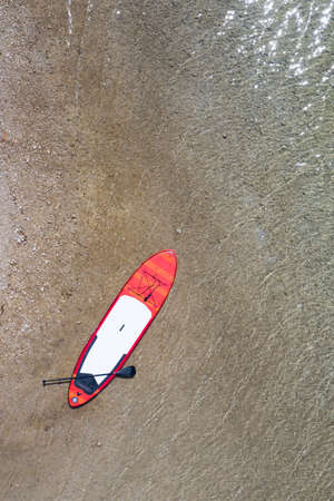top view to Stand-Up-Paddling board at gravel sand shore with clean lake waterの写真素材