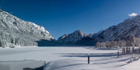 Freshly snowed and frozen lake heiterwangersee on a wonderful sunny winter day with blue skyの写真素材