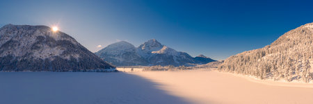 snow-covered frozen lake heiterwangersee in winter with morning sun on the mountain ridge with gentle shadowsの写真素材