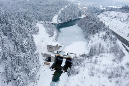 Hydroelectric power station with weir system on the Lech river on the motorway in winter with snow-covered forestの写真素材