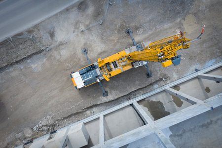 View from above on large heavy truck crane in front of concrete scaffolding of an industrial hallの写真素材