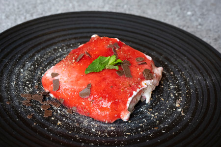 hearty strawberry tiramisu served on a black plate with peppermint, icing sugar and chocolate sprinklesの写真素材