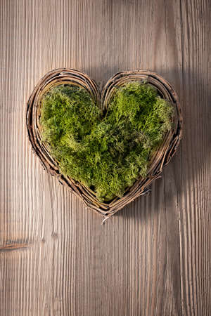 braided heart filled with green moss on old wood background for cover sheetsの写真素材