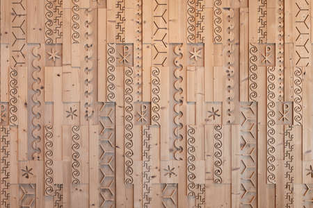 Milled and cut stone pine wooden wall with different patterns and symbolsの写真素材
