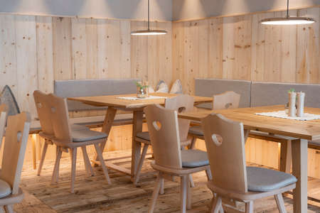 Newly paneled pine wood seating area with chairs and tables with pleasant, light ceiling lightsの写真素材