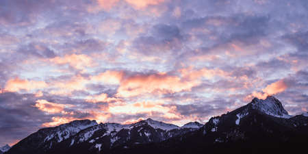 wonderful afterglow cloud play over the snowy hahnenkamm mountain range in tyrol in autumnの写真素材