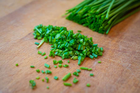 freshly cut green chives on wooden board to decorate main dishの写真素材