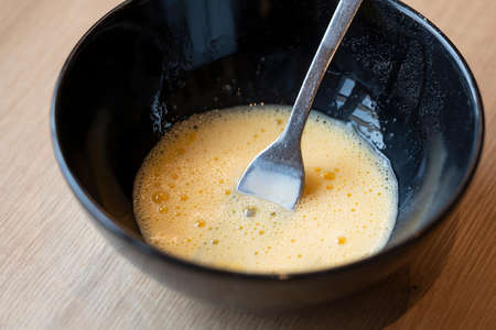 frothy beaten egg yolks and milk glaze in a black bowl to spread pastries like easter braids
