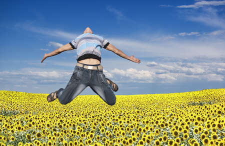 Boy jumping against a background of field and skyの写真素材