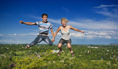 Boy and girl jumping against a background of beautiful skyの写真素材