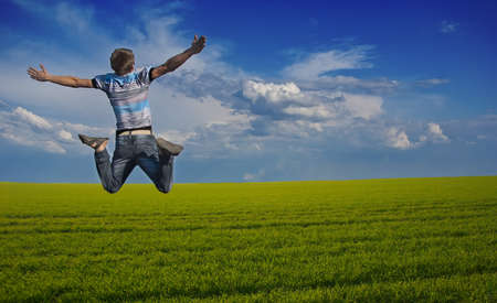 Boy jumping against a background of beautiful sky and meadowの写真素材