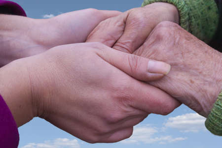 Hands of grandmother and granddaughter against a background of blue skyの写真素材