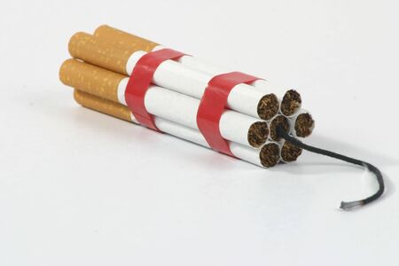 grouped cigarettes together with a lighted string, like a dynamite (bomb) on a white backgroundの写真素材