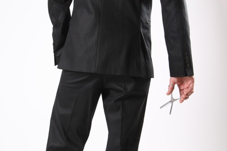 A back of a man holding a scissor in his handの写真素材