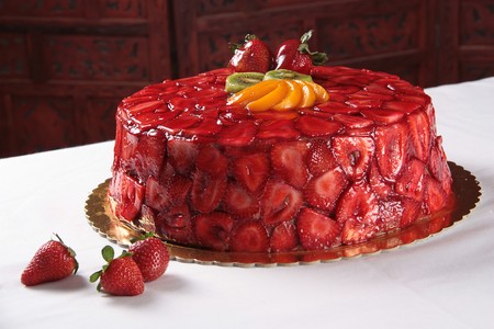 Glossy Strawberry cake with on a table 3 strawberries on a sideの写真素材