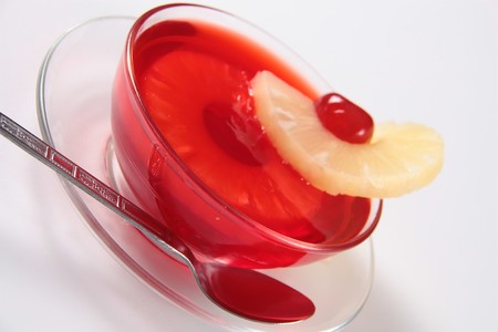 Red jelly plate with pineapple and cherry, on a white backgroundの写真素材
