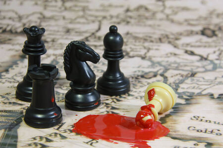 Chess stones on a map, 3 blacks against 1 white, with blood sceneの写真素材