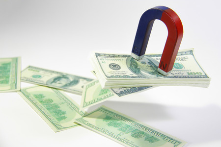 A magnet attracting money papers cultured on a white backgrounの写真素材