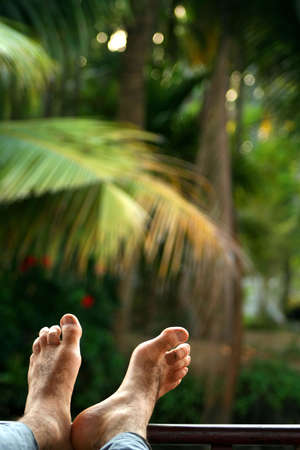 Mens feet on the porch of ship sailing through Kerala backwatersの写真素材