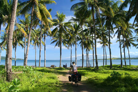 Lonely cyclist traveling through indonesian jungle in Sumbawaの写真素材