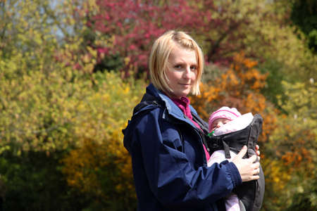 Mother carrying Her daughter In a baby carrierの写真素材