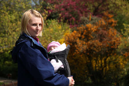 Mother carrying Her daughter In a baby carrierの写真素材