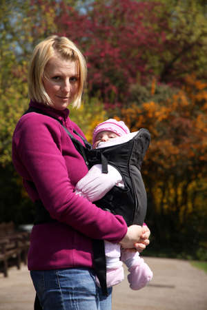 Mother carrying Her daughter In a baby carrierの写真素材