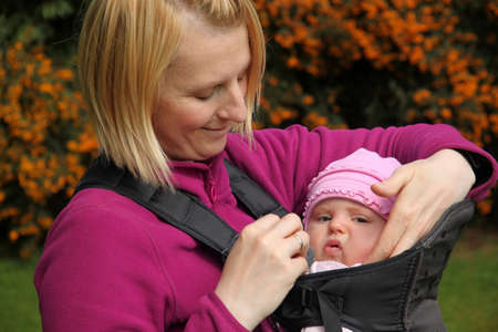 Mother carrying Her daughter In a baby carrierの写真素材