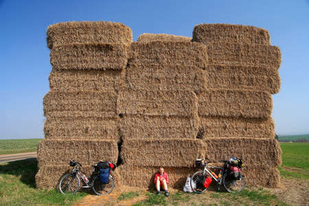 Woman cyclist taking a break next to the high haystack In the field In Czech Republicの写真素材