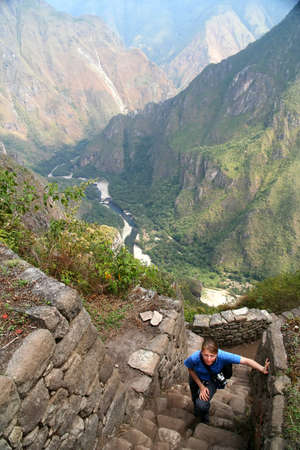 Tourist climbing old incan stairs to the top of Wayna Picchu for the views of Machu Picchu, Peruの写真素材