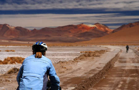 Lonely cyclist on the sandy road in Altiplano in Boliviaの写真素材