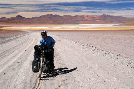 Girl struggling with her bike on a sandy track in Altiplano, Boliviaの写真素材