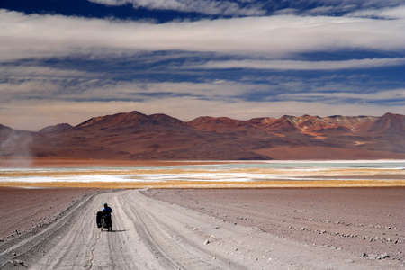 Girl struggling with her bike on a sandy track in Altiplano, Boliviaの写真素材