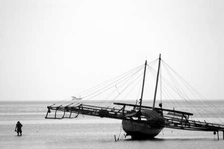 Picture of an old man walking from his boat in the low tide ocean in Sumbava, Indonesiaの写真素材