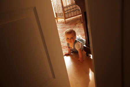 Little baby girl trying to crawl through the open doorsの写真素材