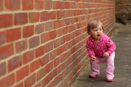 Portrait of cute beautiful little girl against background of a brick wallの写真素材