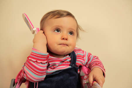 Baby girl pretending to call home on her toy mobile phoneの写真素材