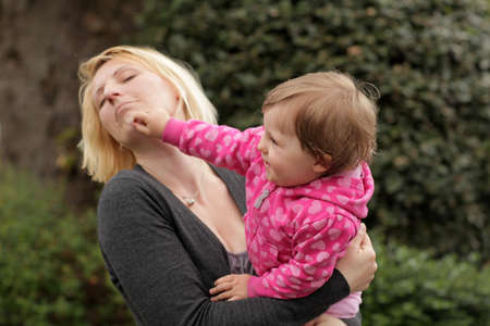 Baby daughter playing with her mum accidently punching herの写真素材