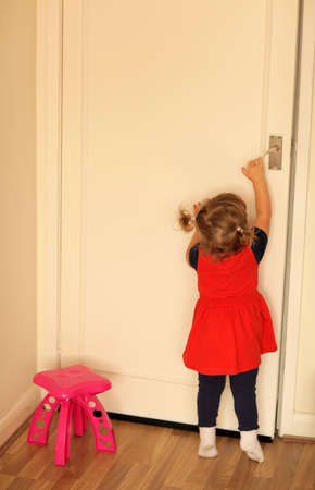 Cute little baby girl trying to open room doorsの写真素材