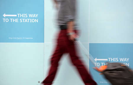 Blurred image of a person passing sign showing direction to the train stationの写真素材