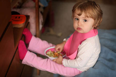 Portrait of a cute little baby girl eating pasta for dinnerの写真素材
