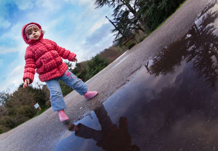 Baby girl standing in front of the puddle after rain in english countrysideのeditorial素材