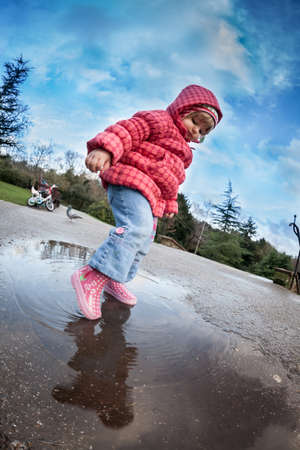 Baby girl standing in front of the puddle after rain in english countrysideのeditorial素材