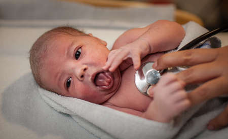 Newborn boy getting his first medical check-up by midwife