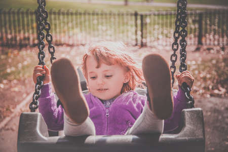 Little baby girl having fun on a sling in a playgroundの写真素材