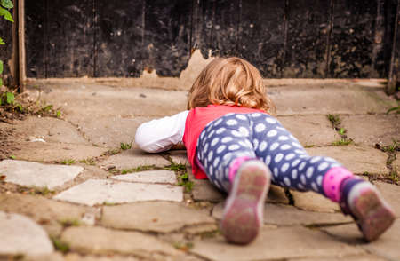 Young girl peeking through the hole in the gates in the gardenの写真素材