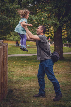 Father catching her daughter jumping from high wooden polesの写真素材